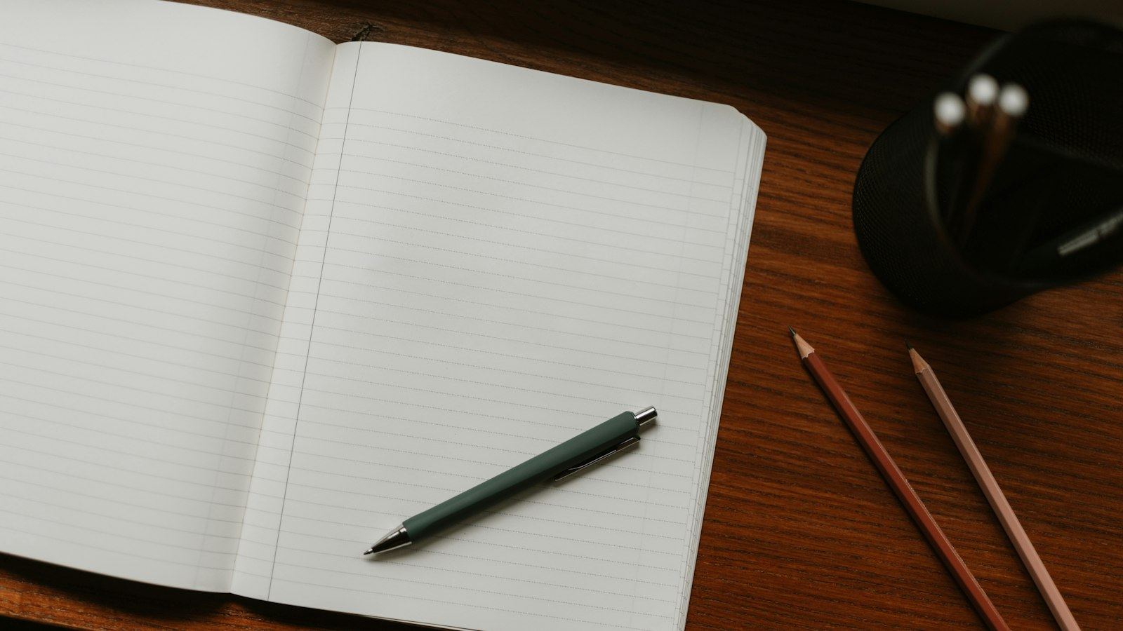 Open notebook with a pen and pencils